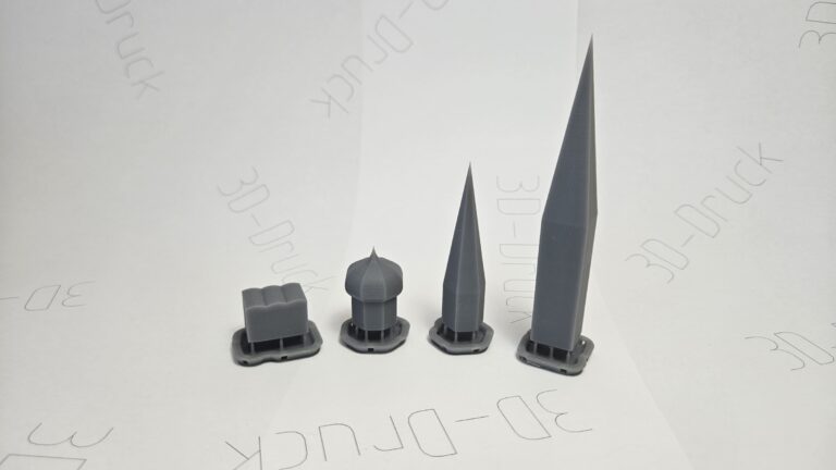 Vier graue 3D-gedruckte Testobjekte in unterschiedlichen Formen