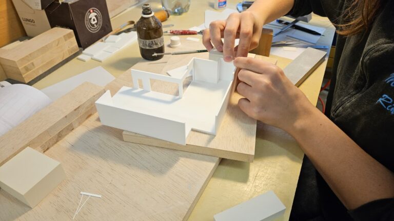 Hände bauen Architekturmodell aus weißem Karton